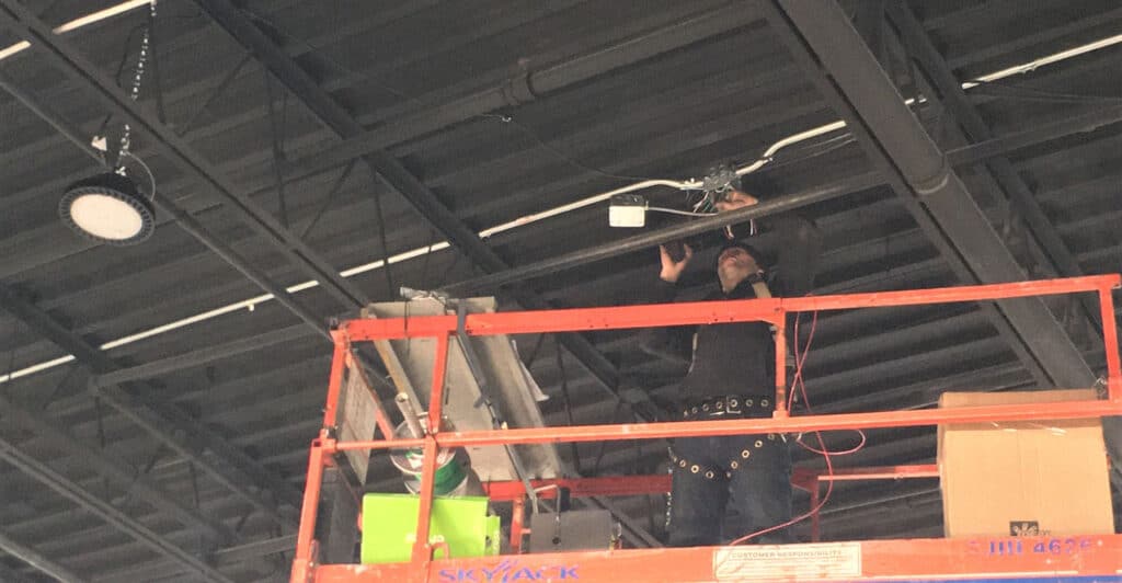 Electrician Installing LED Warehouse Lighting In Ontario, Canada